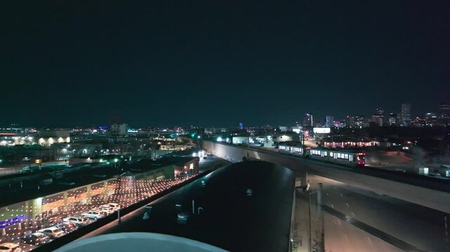 Commuter rail crosses along bridge at night with Denver city skyline in distance