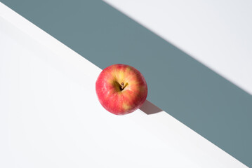 Una manzana roja sobre un soporte blanco y fondo verde. Vista superior	