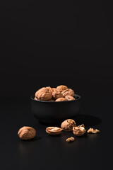 Nueces doradas en un recipiente negro sobre fondo negro	