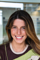 Happy caucasian young student female looking at camera enjoying with a perfect white teeth. Portrait of a joyful and adorable teenage brunette woman posing for a college promotion