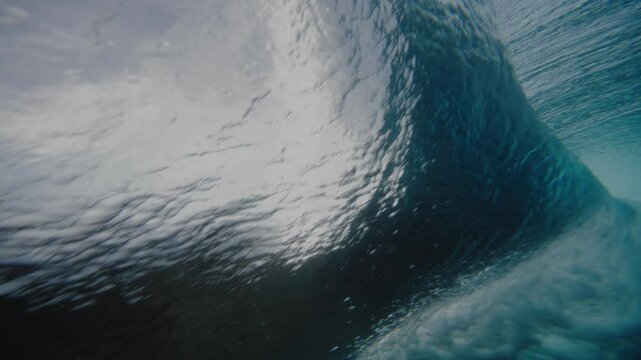 Underwater sideview of strong powerful vortex barrel from behind at Cloudbreak Fiji
