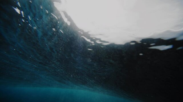 Sun light sparkles across edge of textured water rising into barrel at Cloudbreak Fiji