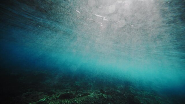 Underwater view of ocean at Cloudbreak fiji as sunlight shines behind barrel