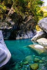 Naklejka premium A vibrant blue river flowing through a dramatic mountain canyon, showcasing the stunning natural beauty and dynamic landscape on Shakadang Trail in Taroko National Park, Hualien, Taiwan