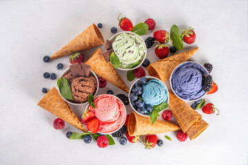 Colorful bright ice cream on bowls, with waffle cones and berries, on white background. Variety of...