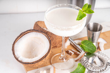 Coconut mint margarita cocktail. Homemade summer cold refreshing coconut milk Lime Margarita with Mint with bar utensils, on white kitchen table