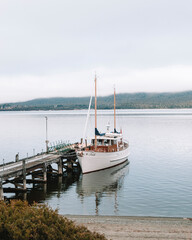 Fototapeta premium Peaceful photograph of a boat docked at the port in Te Anau, New Zealand, with the tranquil waters reflecting the surrounding mountains.