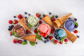 Colorful bright ice cream on bowls, with waffle cones and berries, on white background. Variety of...