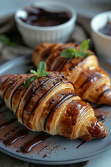 Two croissants with chocolate and mint sauce on top