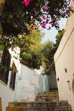 A street with white walls and flowers in Greece. Window with shutters	