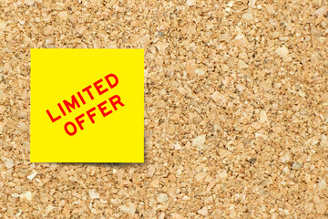 Yellow note paper with word limited offer on cork board background with copy space