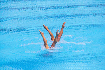 Artistic swimming duet performing synchronized legs movement in swimming pool