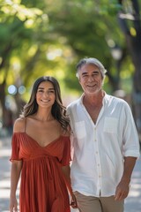 Naklejka premium A middle-aged Asian woman in a red dress and a smiling white man in a white shirt holding hands and walking in a park