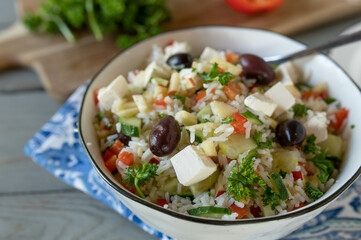 Mediterranean rice salad with peppers, cucumber, apples, olives and feta cheese. Delicious homemade summer food