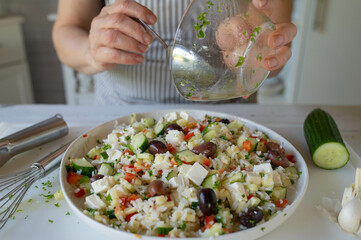 Marinating a fresh and homemade salad by woman´s hand on kitchen counter