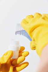 Woman in yellow gloves pouring hand sanitizer from bottle into another woman's hand
