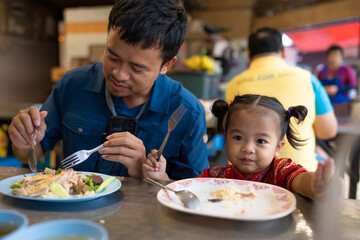 Adorable little asian girl eat steam rice with dad on street food local city Yaowarat