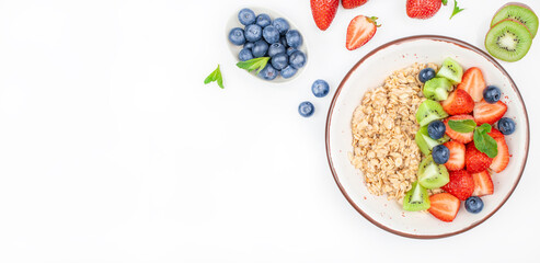 Oatmeal porridge with fruit and berries strawberry, kiwi, blueberry in bowl on white table, healthy...