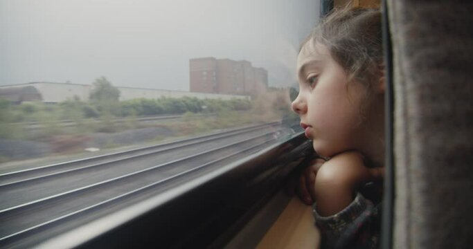 Portrait of a little girl looking out the train window. Her face reflects a sense of adventure and exploration, creating an image full of childlike innocence and anticipation of new discoveries.