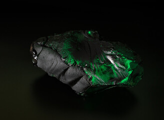 black stone with a green backlight lies on a black background