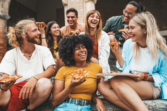 Fototapeta Multicultural smiling friends eating pizza sitting outside - Cheerful young people enjoying summer vacation together - Happy life style concept with guys and girls hanging out on a sunny day