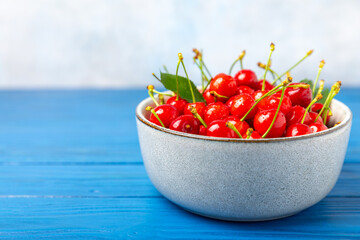 Cherries. Fresh ripe cherries with leaves on a textured wooden background. Fresh sweet organic cherry pile. Berries and fruits. Vegan. Healthy eating. Place for text. Copy space