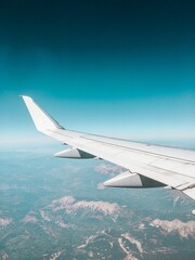 Obraz premium Wing on Airplane Flying over Mountains