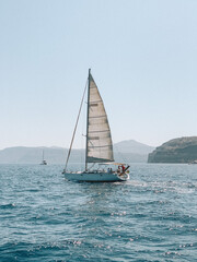 Naklejka premium Serene photograph of a boat gliding across the Aegean Sea near Santorini, Greece