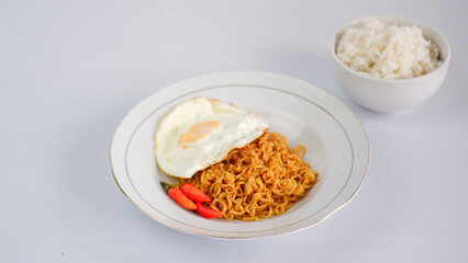 Fried noodles with fried egg and red cayenne pepper, served on a serving plate. Isolated on white background.