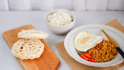 fried noodles with fried egg and crackers are served on a plate on a white table. Ready to eat concept.