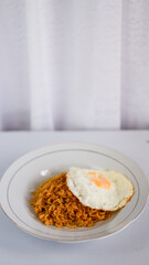 Fried noodles with fried egg and red cayenne pepper. Served on a serving white plate. Isolated on white background.