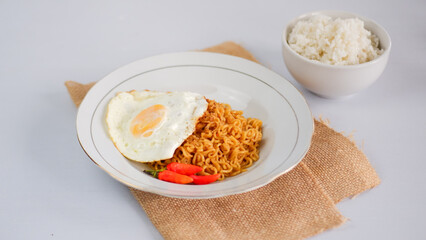 Fried noodles with fried egg and red cayenne pepper, served on a serving plate. Isolated on white background.
