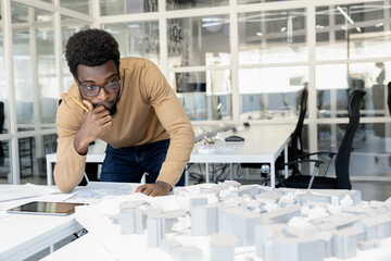 African american architect thinking on a miniature and looking thoughtful