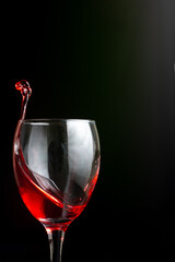 Red liquid is being poured into a wine glass on a table