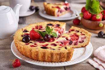Tart with cherries strawberries and custard milk cream filling. Open cheesecake pie. Delicious homemade summer dessert with berries. 