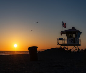 Lifeguard Tower Against Setting Sun, Many Distant People Watching Plus Unknown Lifeguard in Tower, April 24, Huntington Beach, California, USA, square