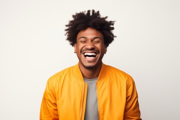 Portrait of a joyful afro-american man in his 20s wearing a trendy bomber jacket on white background