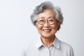 Fototapeta premium Portrait of a grinning asian elderly woman in her 90s donning a classy polo shirt isolated in white background