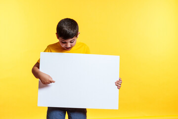 A young boy is holding a white sign and pointing to the right