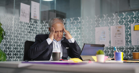 Indian Asian gen x tensed older adult busy boss man sitting suffer pain head ache health issue...