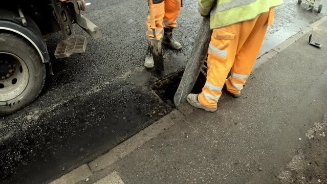 Workers repairing road gully sewer on city street