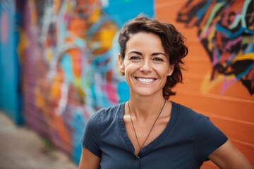 Naklejka premium Portrait of a smiling woman in her 40s wearing a sporty polo shirt over colorful graffiti wall
