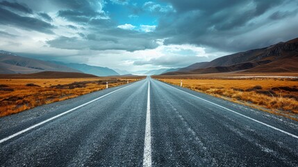Fototapeta premium Scenic Long Road in Mountain Landscape Under Dramatic Sky Travel Inspiration, Adventure, and Nature Photography
