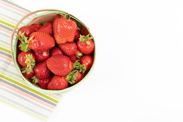 A basket full of strawberries on a colorful towel on a white table