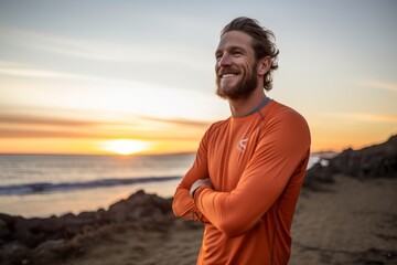 Portrait of a smiling man in his 30s showing off a lightweight base layer isolated in vibrant sunset horizon
