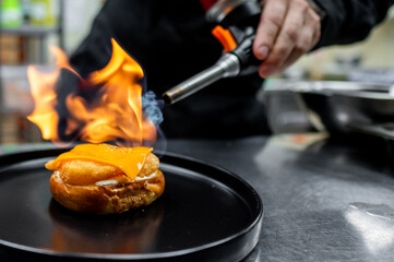 preparing a gourmet cheeseburger on restaurant kitchen with fire