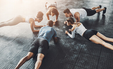 People, fitness and plank in group at gym for workout, core exercise or training together indoors. Diverse class, friends and warm up for ab muscle, session and sport for health above gymnasium floor