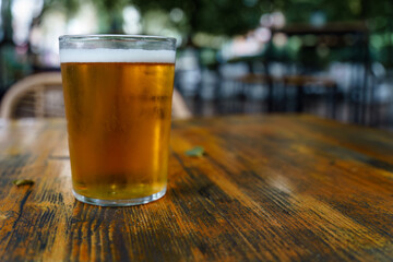 Full glass of beer on a wooden restaurant table