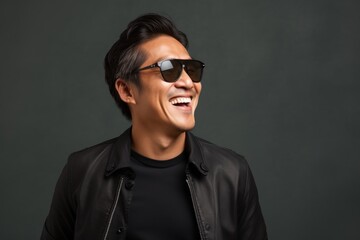 Obraz premium Portrait of a joyful asian man in his 40s wearing a trendy sunglasses in front of modern minimalist interior