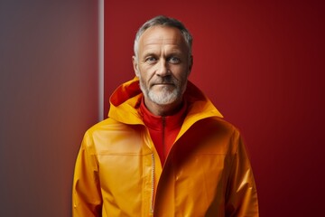 Fototapeta premium Portrait of a content man in his 50s wearing a vibrant raincoat in front of modern minimalist interior